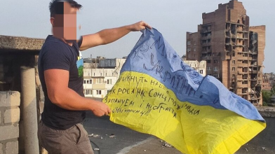 В окупованому Маріуполі розгорнули прапор України на фоні зруйнованих будинків